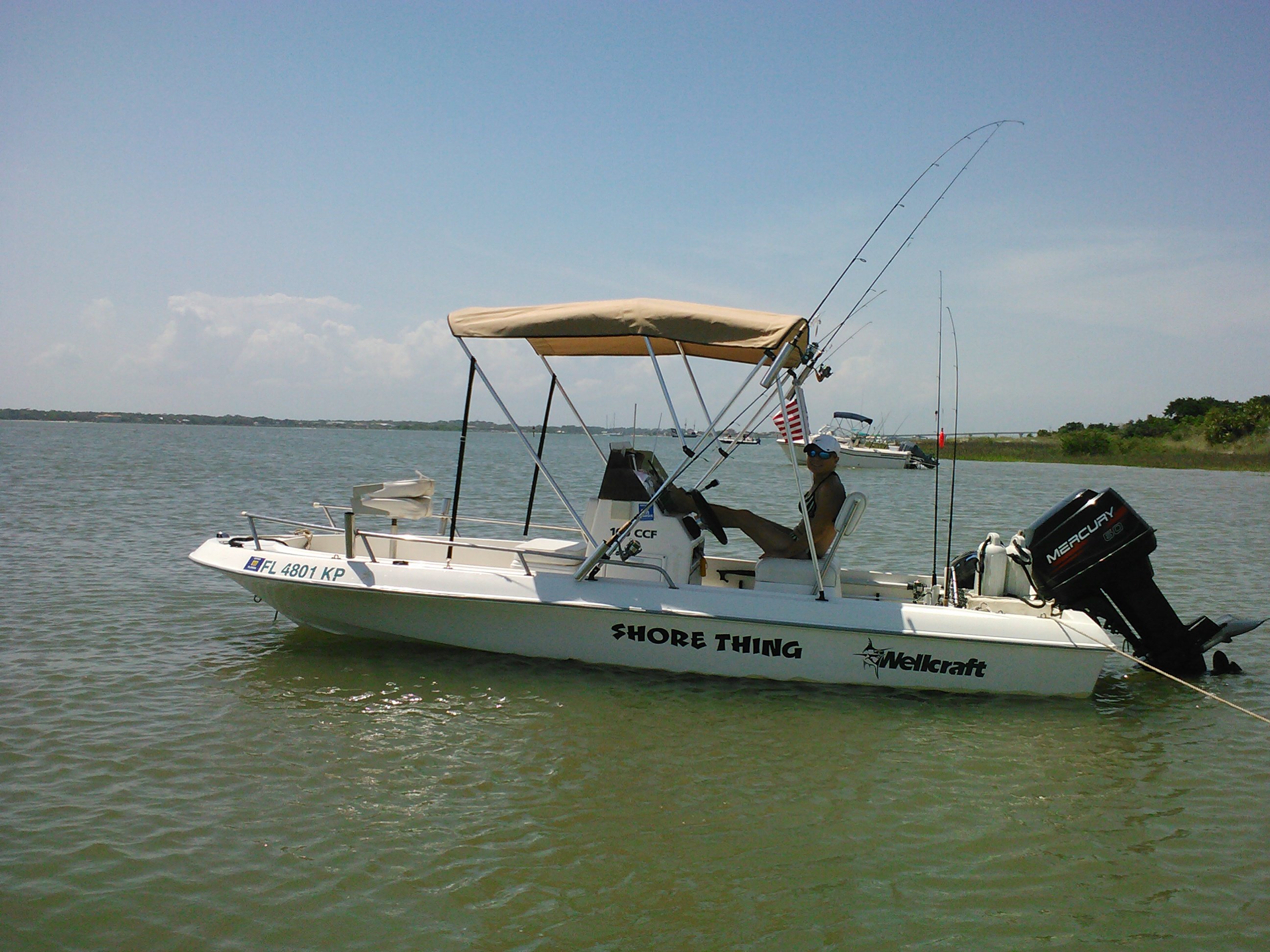 man sitting on his fishing boat under the Bimini top